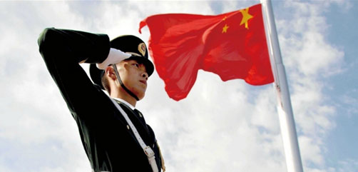 A Chinese soldier salutes the red, five-starred national flag of the People's Republic of China at the raising ceremony in Beijing on 1 Oct 2014.- ALLOW IMAGES