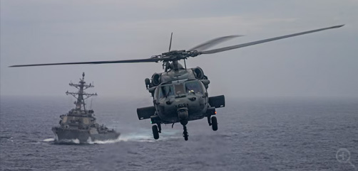 A Navy MH-60S Sea Hawk helicopter flies past the USS Decatur as it approaches the flight deck of the USS Nimitz in the Pacific Ocean, June 12, 2023. Image: DoD - ALLOW IMAGES