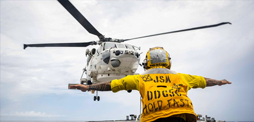 Navy Petty Officer 3rd Class Zachary Kai signals a Japanese helicopter to land on the flight deck of the USS John S. McCain during flight operations in the South China Sea, Oct. 12, 2020. - ALLOW IMAGES