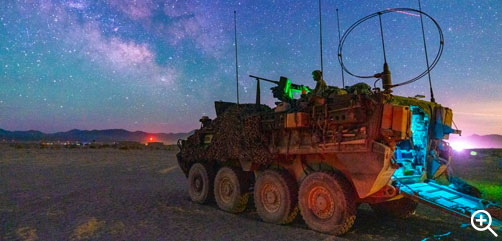 Click to Enlarge - Army Sgt. Justin Covert mans an M1A2 .50-caliber machine gun on a Stryker vehicle during training at Fort Irwin, Calif., as the Milky Way galactic center is visible overhead, May 24, 2022. - ALLOW IMAGES